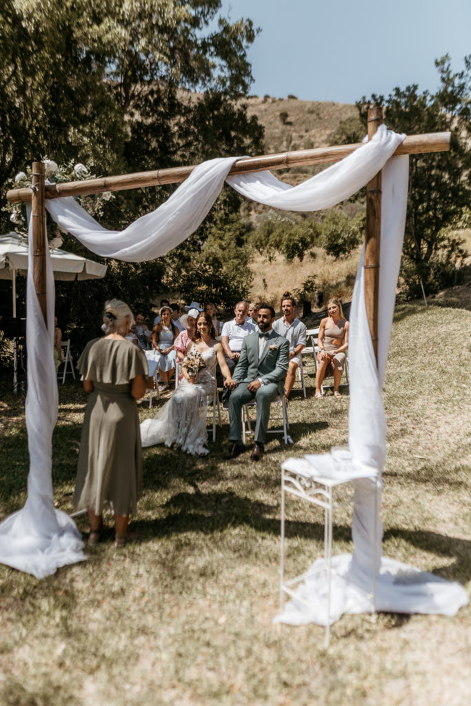 a group of people sitting in chairs under a wooden arch