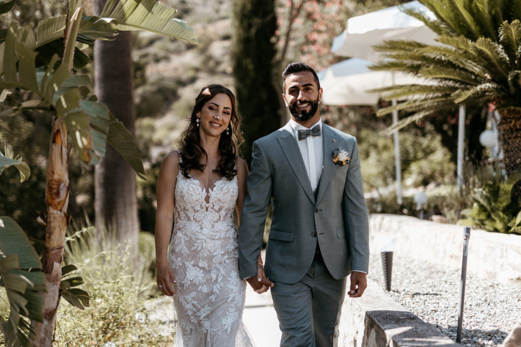 a man and woman holding hands and walking down a path