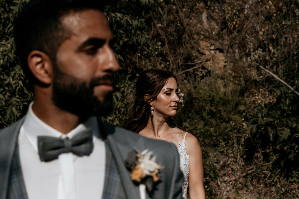 a man and woman standing in front of bushes