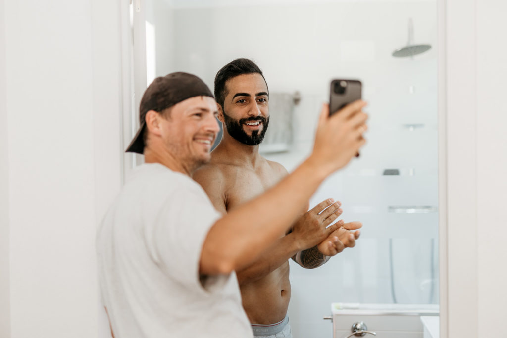 a man taking a selfie with another man in the mirror