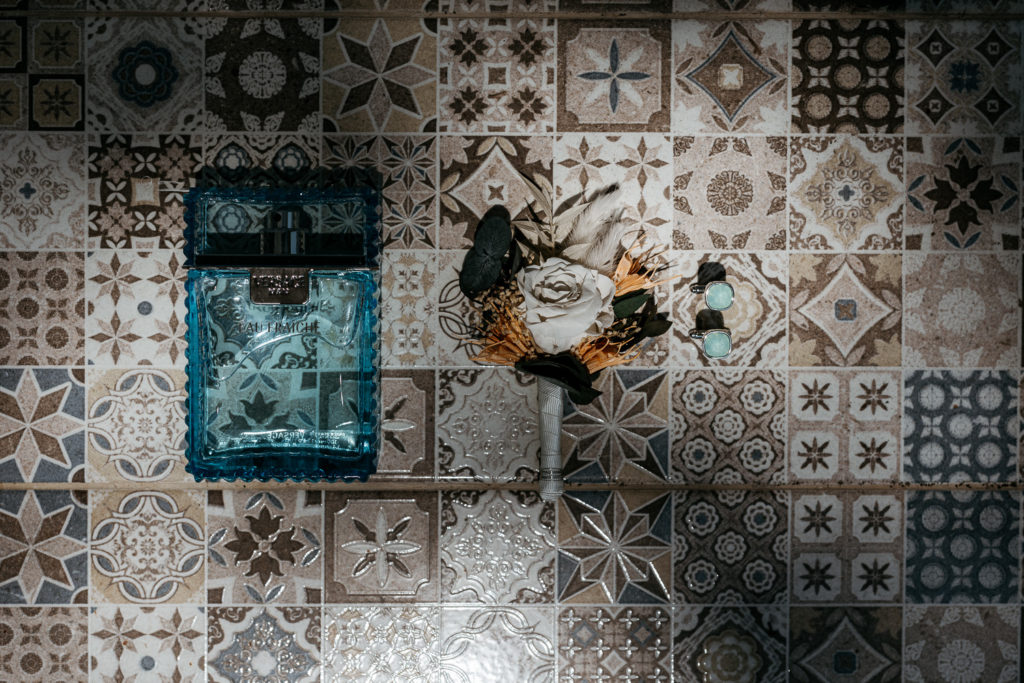 a boutonniere and perfume on a tile floor