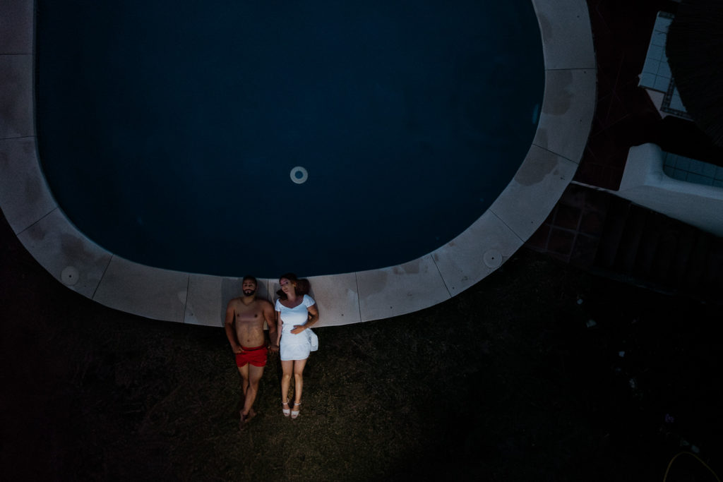 a man and woman lying on the ground next to a pool