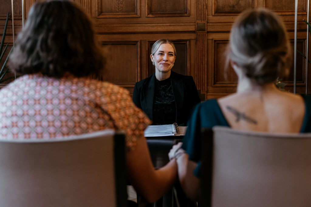 a woman sitting at a table with other women holding hands